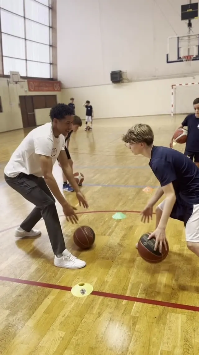 Un coach et un jeune joueur dribblent face à face au gymnase